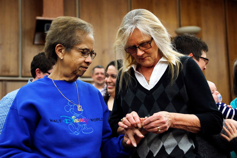 Pennye Mattson, right, places a wedding ring on Sherrie Tyler, left, while being married in a group by the Oakland County Clerk in Pontiac, Mich., March 22, 2014.