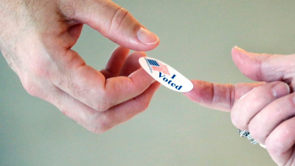 A Madison, Miss., precinct worker offers a voter a "I voted" sticker after voting in party primaries on Tuesday, June 3, 2014.