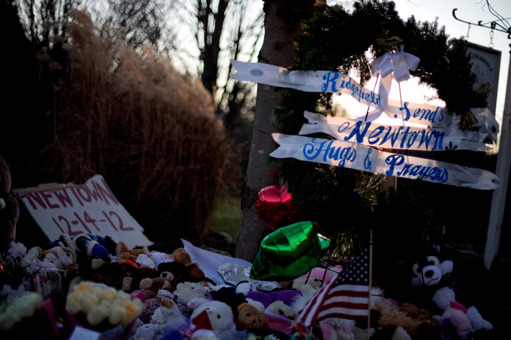 The sun sets behind a memorial for the Sandy Hook Elementary School shooting victims, Wednesday, Dec. 19, 2012, in Newtown, Conn.