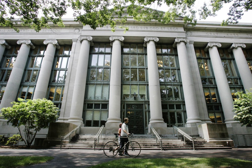 A bicyclist walks by Langdell Hall, the Harvard Law Library, on the campus of the Harvard Law School in Cambridge, Mass., Aug. 1, 2005. (Photo by Charles Krupa/AP)