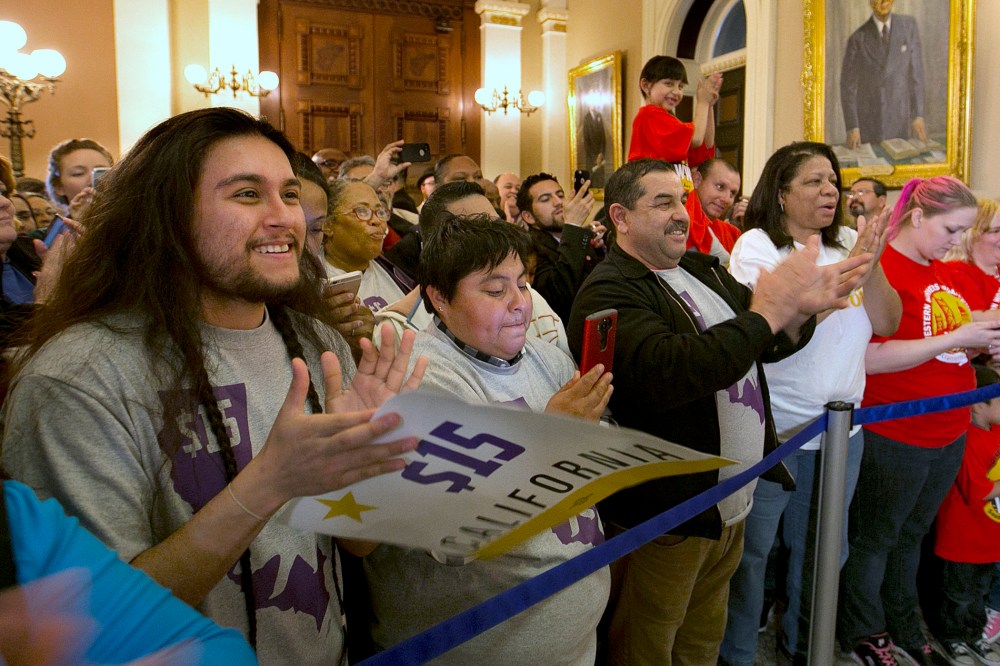 Supporters of a bill to raise California's minimum wage, celebrate outside the state Senate Chamber after the measure was approved by the Senate, March 31, 2016, in Sacramento, Calif. (Photo by Rich Pedroncelli/AP)