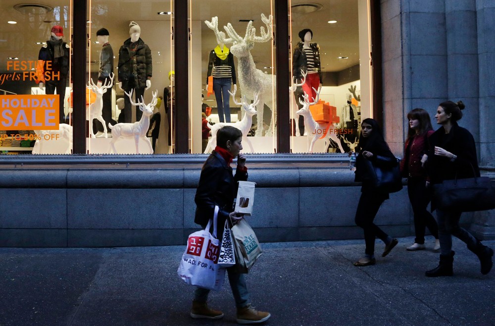 In this Friday, Nov. 22, 2013 photo, shoppers walk past windows at a Joe Fresh clothing store in New York.