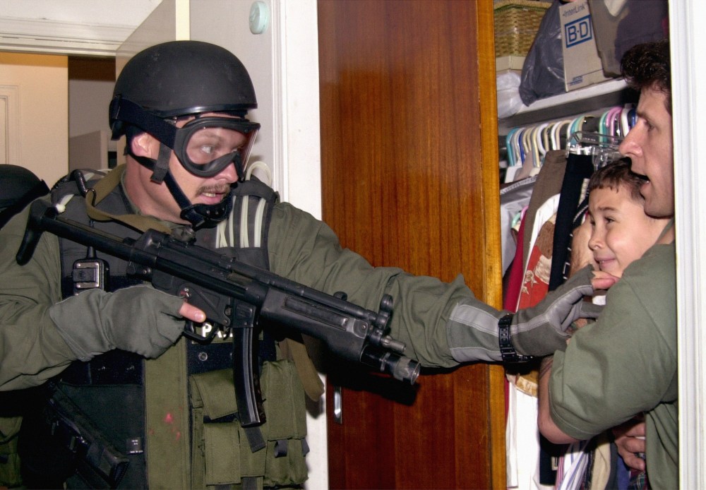 In this fourth of seven sequential photos, Elian Gonzalez is held in a closet by Donato Dalrymple, right, as government officials search the home of Lazaro Gonzalez for the young boy, early Saturday morning, April 22, 2000, in Miami. (AP Photo/Alan Diaz)