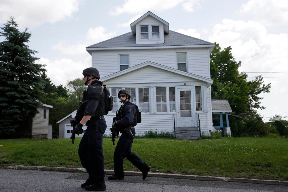 Law enforcement officers walk the streets near the prison in Dannemora, N.Y., as they searched houses near the maximum-security prison in northern New York where two killers escaped using power tools, June 10, 2015.