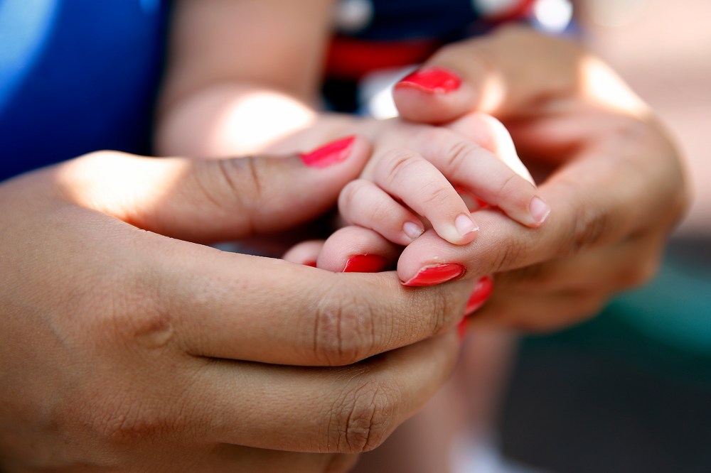 A young girl grasps the hand of her newborn daughter. (Photo by Marc Piscotty/The Washington Post/Getty)