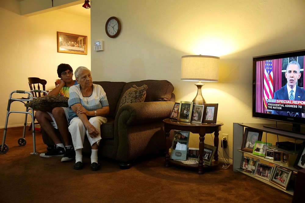 Jonathan Tovar and his grandmother Helen Medina in her house, which was hit by bullets in a gun battle between police and terror suspects, watch President Obama's address, Dec. 6, 2015 in San Bernardino, Calif. (Photo by Joe Raedle/Getty)