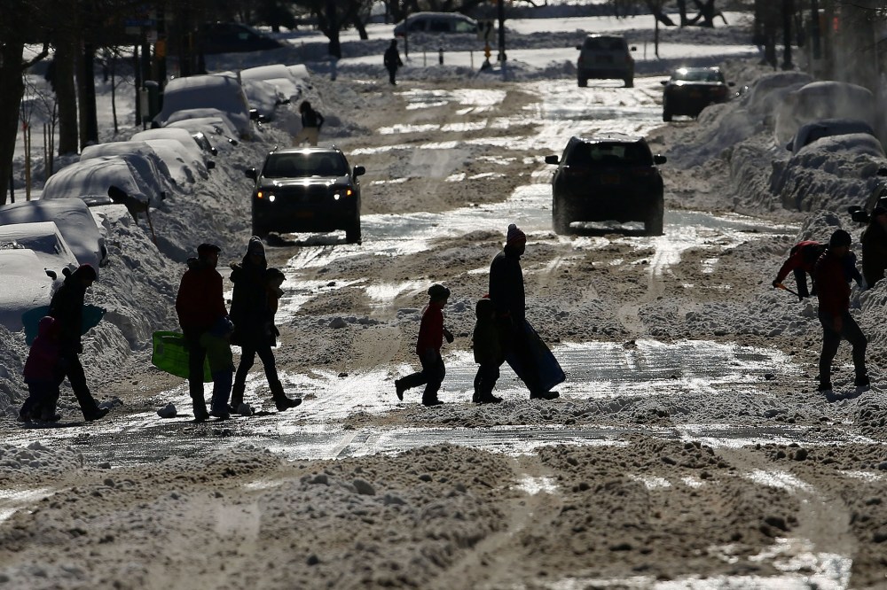 People cross a snow covered street on a sunny day following a blizzard on Jan. 24, 2016 in the Brooklyn borough of New York City. (Photo by Spencer Platt/Getty)