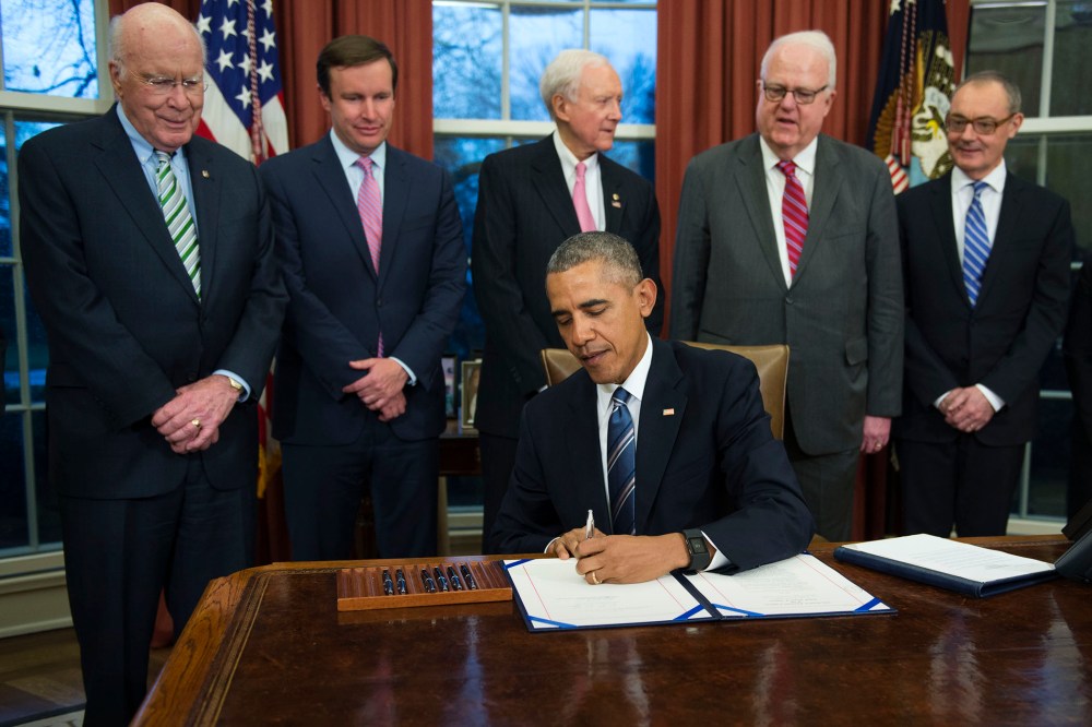 President Barack Obama, flanked by lawmakers and supporters of the bill, signs H.R. 1428 during a ceremony in the Oval Office of the White House on Feb. 24, 2016 in Washington, DC. (Photo by Shawn Thew/Pool/Getty)