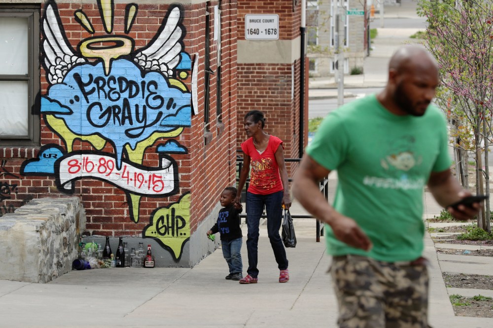 Neighbors walk past the spot where Baltimore police arrested Freddie Gray at the Gilmor Homes in the Sandtown neighborhood one year after Gray died April 19, 2016 in Baltimore, Md. (Photo by Chip Somodevilla/Getty)