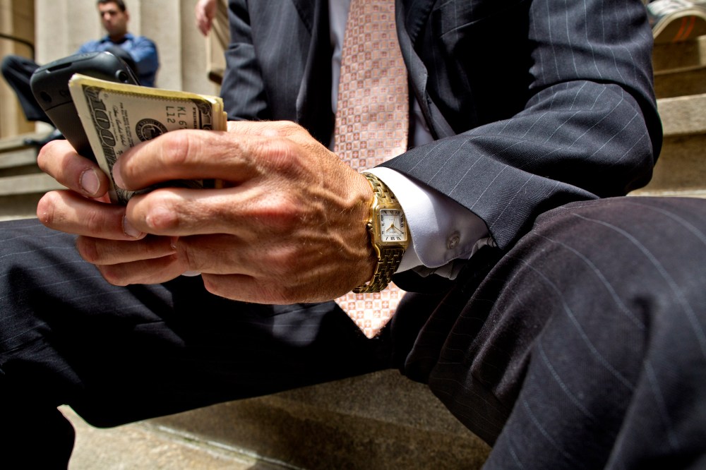 A businessman holding a cellphone and money in downtown Manhattan.