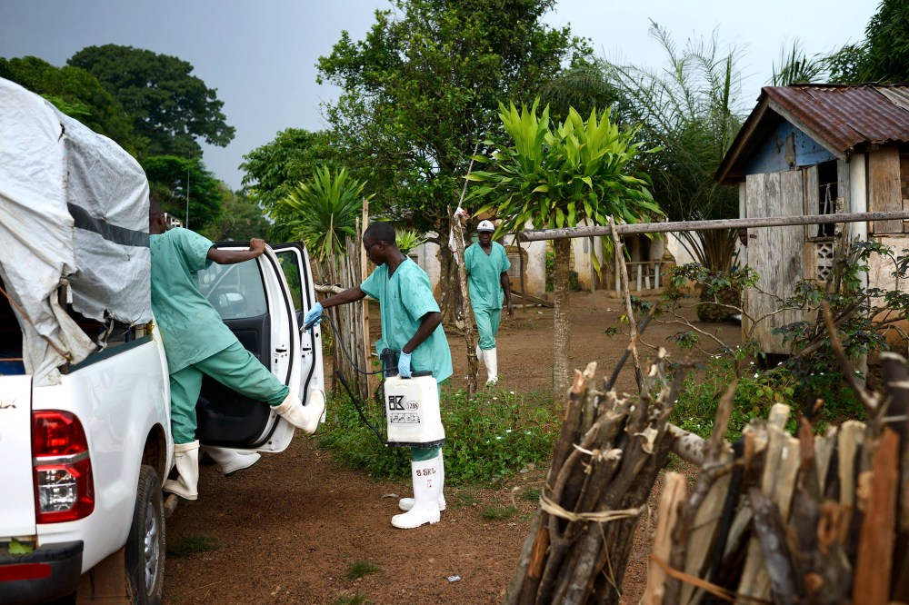 Doctors Without Borders workers wearing protective clothing disinfect materials at a clinic in Teldou, Guinea, July 10, 2014.
