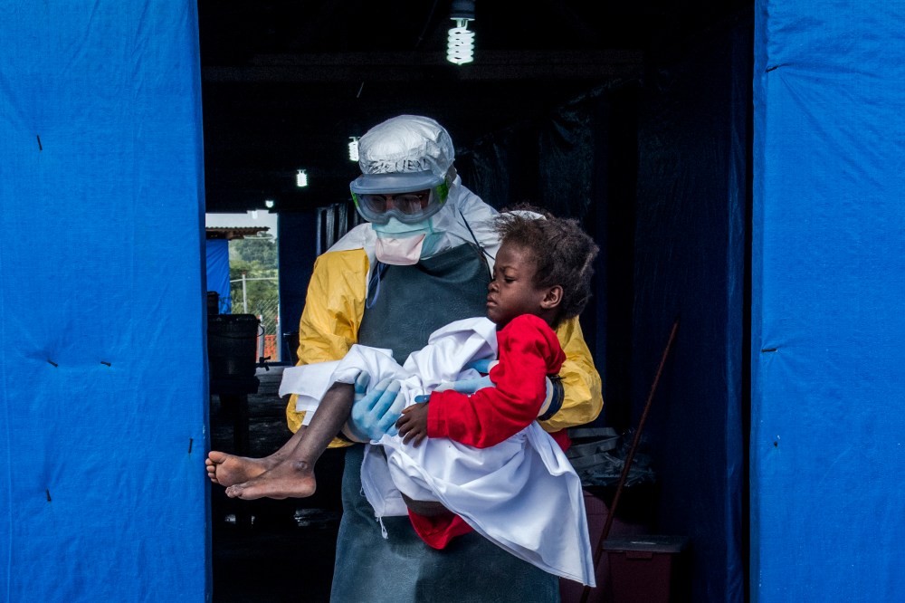 Dr. Steven Hatch carries Blessing Gea, 9, from the suspected ward to the confirmed high-risk ward after a blood test showed her positive for Ebola, at a clinic run by the International Medical Corps in the Suakoko of Liberia, Oct. 10, 2014.