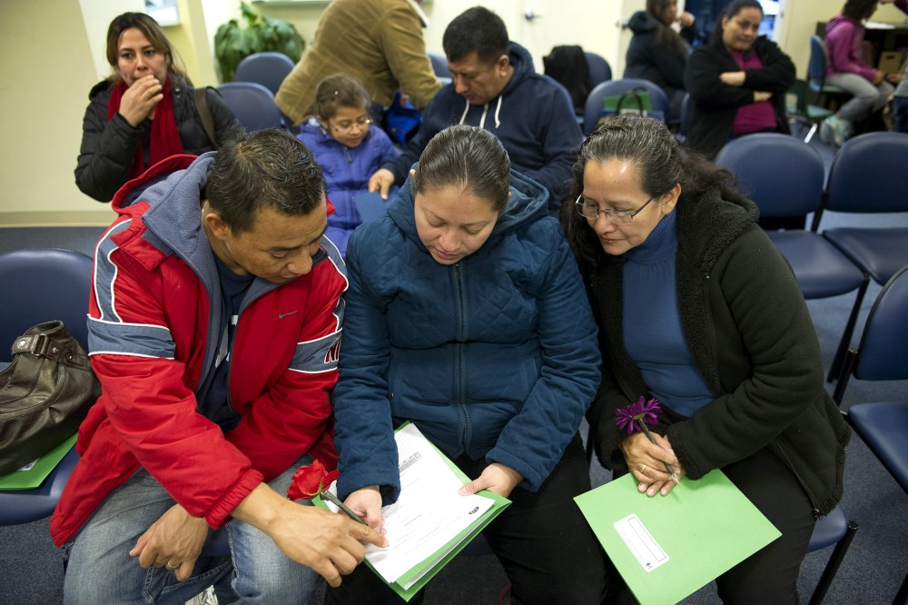 Jasmine Contreras, center, her husband Henry Valerio, left, and mother, Avida Flores, all from Dumfries, Va., fill-out a health care insurance application in Manassas, Va., on Nov. 15, 2014.