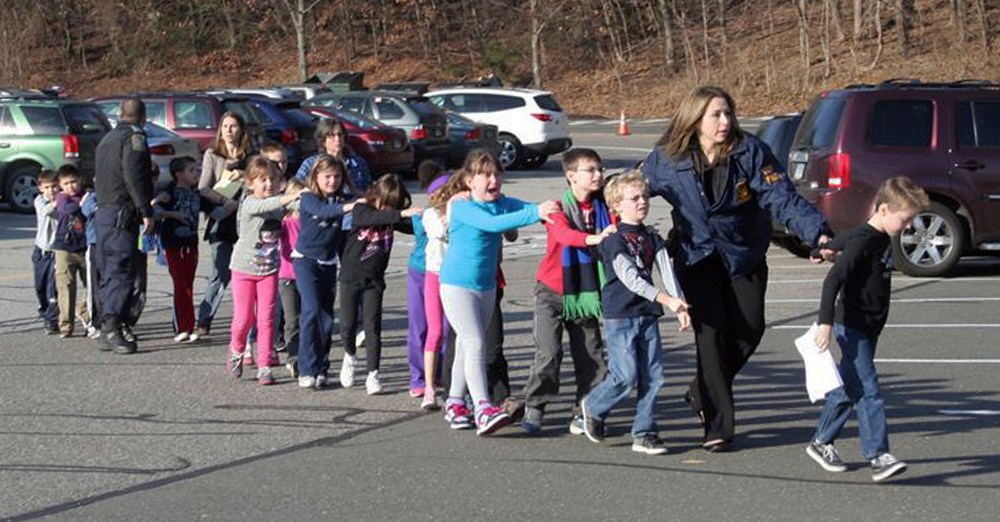 Connecticut State Police lead children from the Sandy Hook Elementary School in Newtown, Conn., following a mass shooting. (Photo by Shannon Hicks/AP Photo)