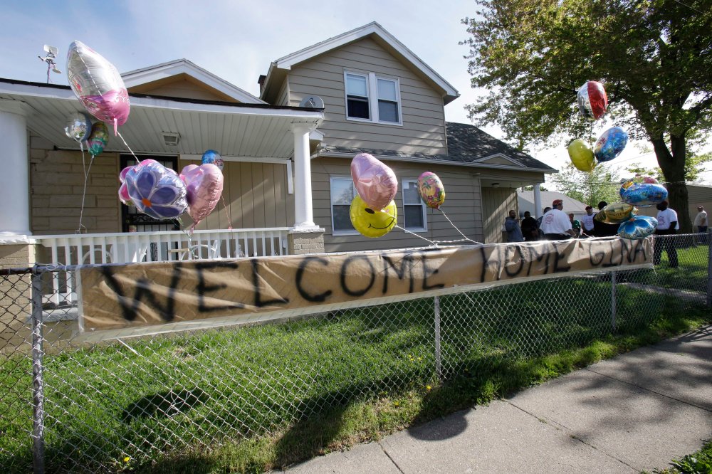 A "Welcome Home Gina " sign hangs on a fence outside the home of Gina DeJesus  Tuesday, May 7, 2013, in Cleveland.  DeJesus, Amanda Berry and Michelle Knight, who went missing separately about a decade ago, were found in a home just south of downtown...