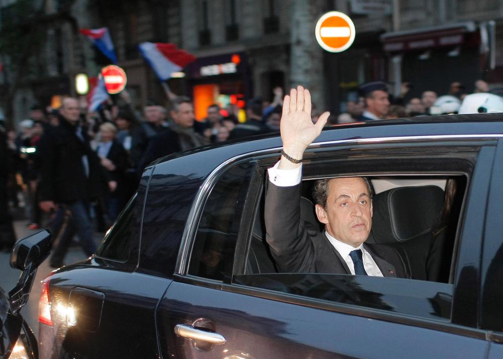 Outgoing French President Nicolas Sarkozy waves from his car as he leaves after addressing supporters at his Union for a Popular Movement (UMP) party headquarters after the the preliminary results of the second round of the presidential elections were...