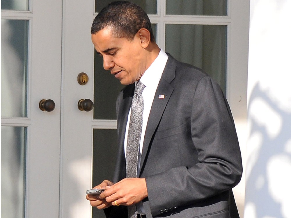 President Obama works on his Blackberry on his belt as he returns to the Oval Office at the White House. (Photo by Ron Sachs-Pool/Getty Images)