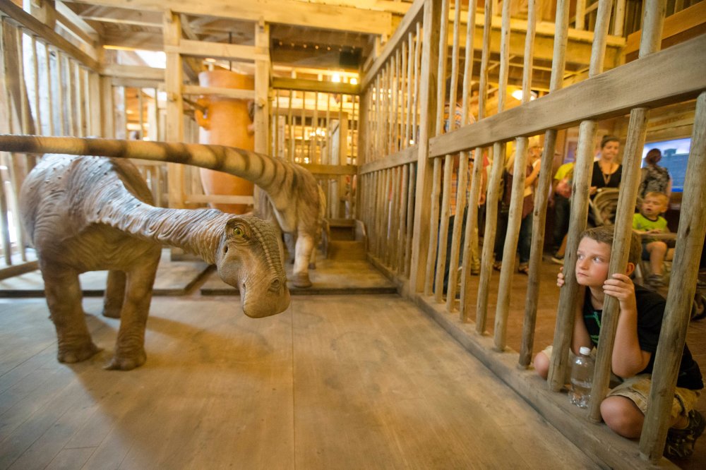 A visitor looks into a cage containing a model dinosaur inside a replica Noah's Ark at the Ark Encounter theme park during a media preview day, Tuesday, July 5, 2016, in Williamstown, Ky.