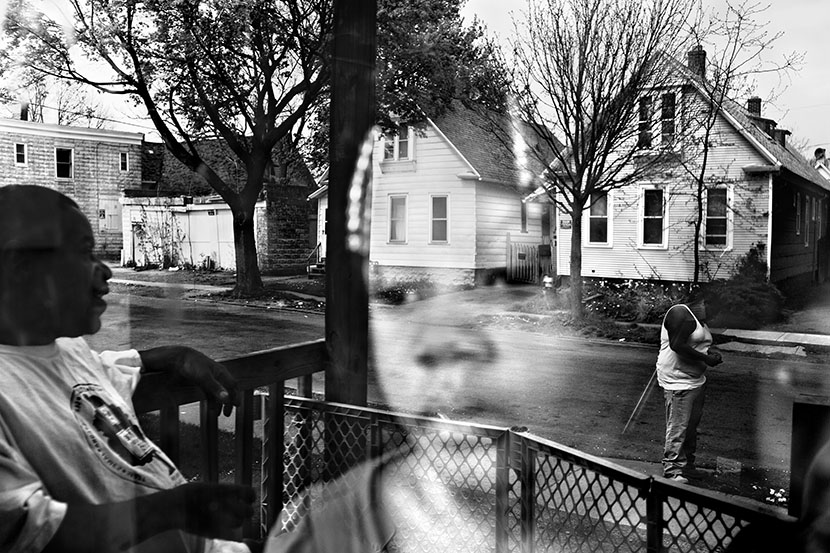 A young child is reflected in a window with her family in the Crescent area of Rochester, NY. (Photo by Paolo Pellegrin/Magnum)