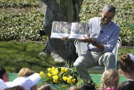 U.S. President Barack Obama laughs as he reads the storybook "Where the Wild Things Are" during the annual Easter Egg Roll at the White House in Washington