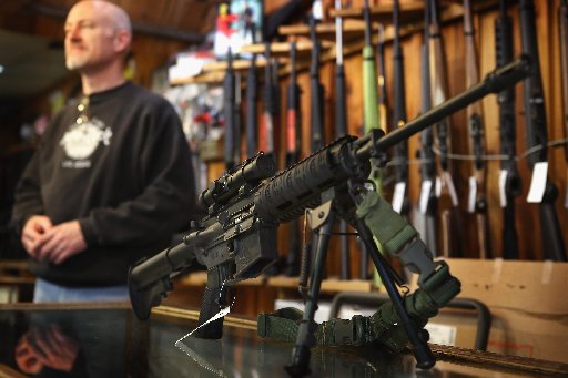 An AR-15 style rifle sits on the counter by Craig Marshall as he assists a customer at Freddie Bear Sports sporting goods store on December 17, 2012 in Tinley Park, Illinois. (Photo by Scott Olson/Getty Images)