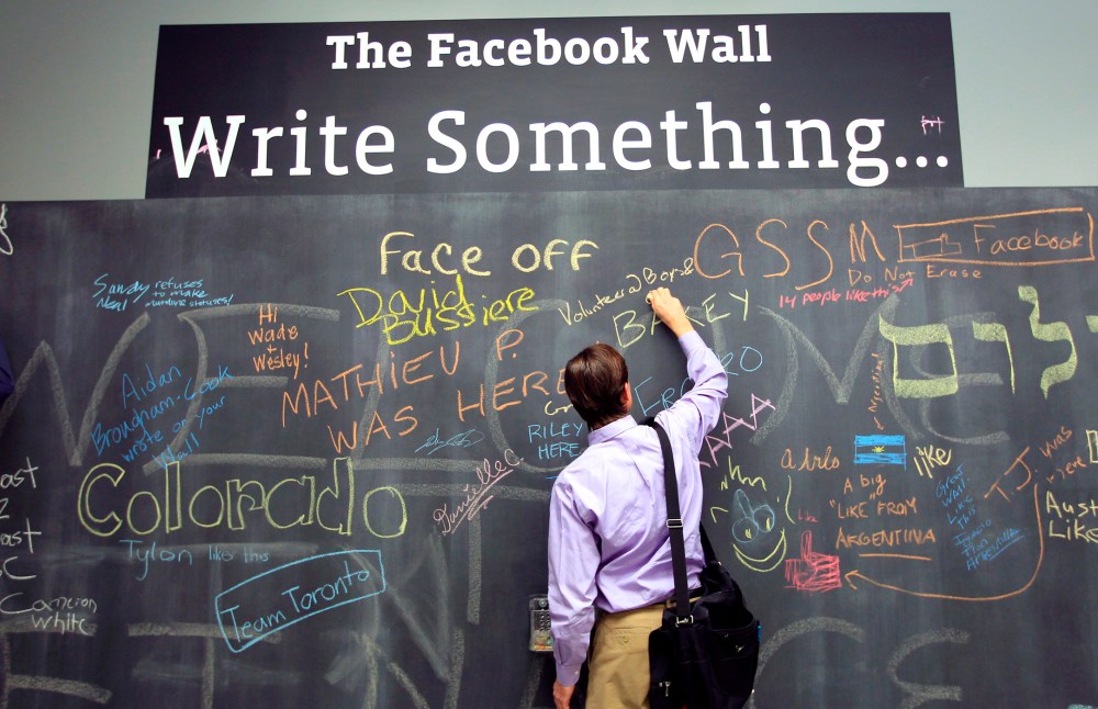 An employee writes a note on the message board at the new headquarters of Facebook in Menlo Park, Calif., Jan. 11, 2012. (Photo by Robert Galbraith/Reuters)