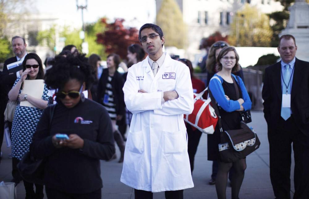 Doctor Vivek Murthy stands among other bystanders during the first day of legal arguments over the Affordable Care Act outside the Supreme Court in Washington March 26, 2012.