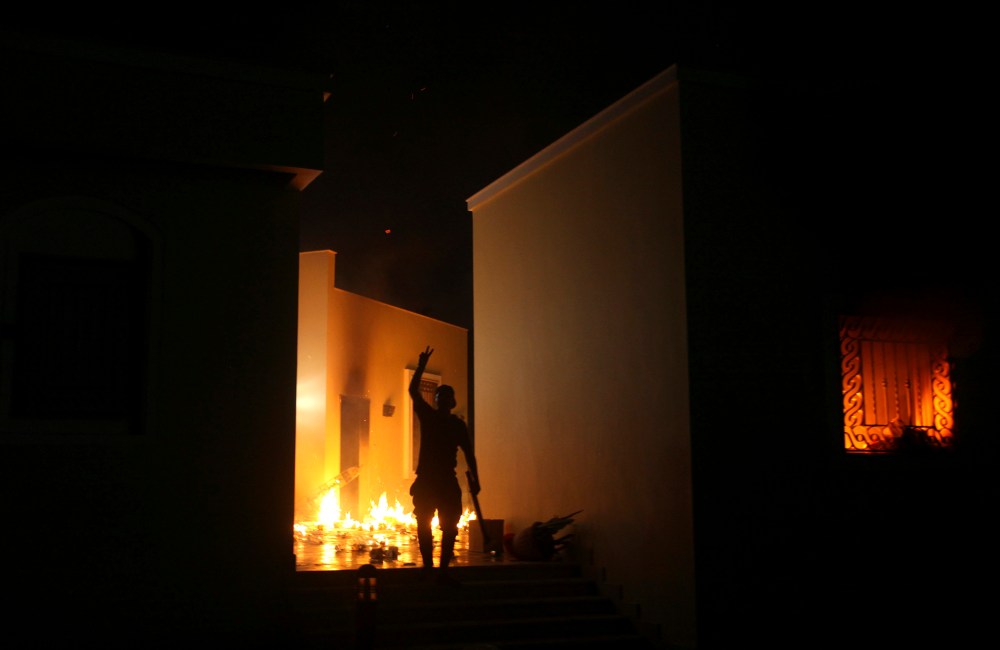 A protester reacts as the U.S. Consulate in Benghazi is seen in flames