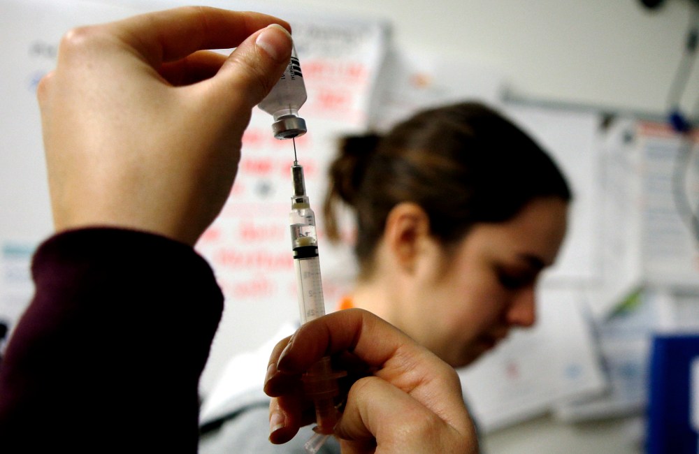 Nurses prepare influenza vaccine injections during a flu shot clinic in Boston