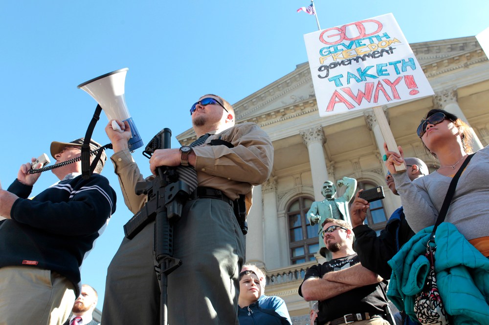 Michael Rugh (2nd-L) holds a AR-15 rifle as he participates along with David Mace (L) and Luchie Wooten (R), during the Guns Across America pro-gun rally at the State Capitol in Atlanta, Georgia, Jan. 19, 2013