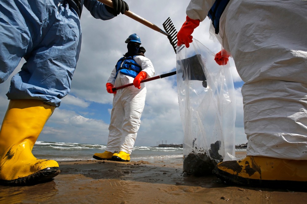 Oil spill response contractors clean up crude oil on a beach after a BP oil spill on Lake Michigan, March 25, 2014, in Whiting, Indiana.