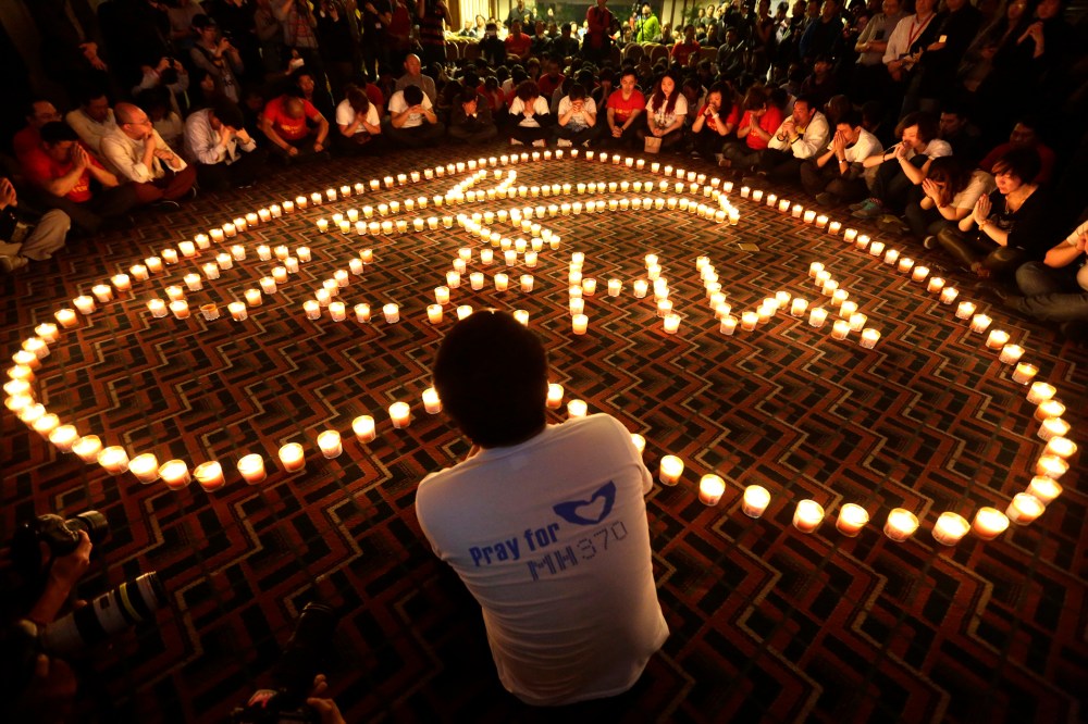 Relatives of passengers onboard Malaysia Airlines Flight MH370 pray during a candlelight vigil in the early morning, in Beijing on April 8, 2014. (Photo by Jason Lee/Reuters)