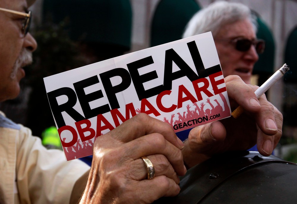 A small group demonstrates prior to former South Carolina Senator Jim DeMint's speech at a "Defund Obamacare Tour" rally in Indianapolis, August 26, 2013.