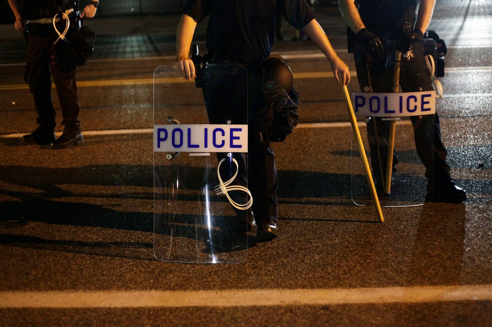Police officers in riot gear stand in position as demonstrators protest the shooting death of Michael Brown, in Ferguson, Mo., on Aug. 19, 2014. (Photo by Joshua Lott/Reuters)