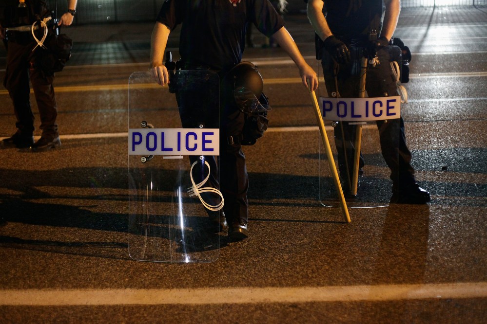 Police officers in riot gear stand in position as demonstrators protest the shooting death of Michael Brown, in Ferguson, Mo., Aug. 19, 2014. (Photo by Joshua Lott/Reuters)