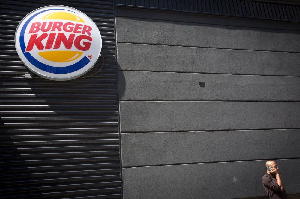 A man talks on his phone underneath a Burger King logo outside the restaurant in the Brooklyn borough of New York