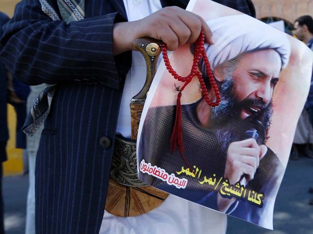 A Shi'ite protester carries a poster of Sheikh Nimr al-Nimr during a demonstration outside the Saudi embassy in Sanaa, Oct. 18, 2014. (Photo by Khaled Abdullah/Reuters)