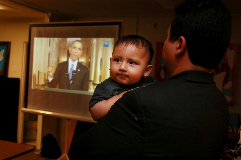 Christian Ramirez holds his nine-month old son Diego while watching President Barack Obama's White House speech on immigration at a viewing party at Alliance San Diego in San Diego, Calif., Nov. 20, 2014. (Photo by Sandy Huffaker/Reuters)