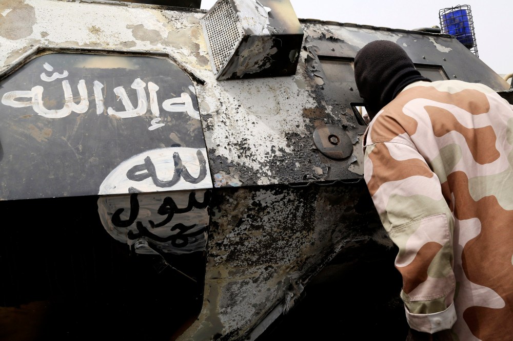 A Chadian soldier peers into a burnt armored vehicle, which the Chadian military say belonged to insurgent group Boko Haram, after the Chadians destroyed it during battle in Gambaru, Feb. 26, 2015. (Photo by Emmanuel Braun/Reuters)