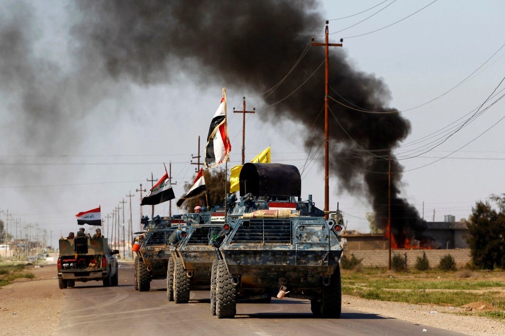 Armored vehicles of Iraqi security forces with militias known as Hashid Shaabi are driven past smoke arising from a clash with Islamic State militants in the town of al-Alam, Tikrit, March 10, 2015. (Photo by Thaier Al-Sudani/Reuters)