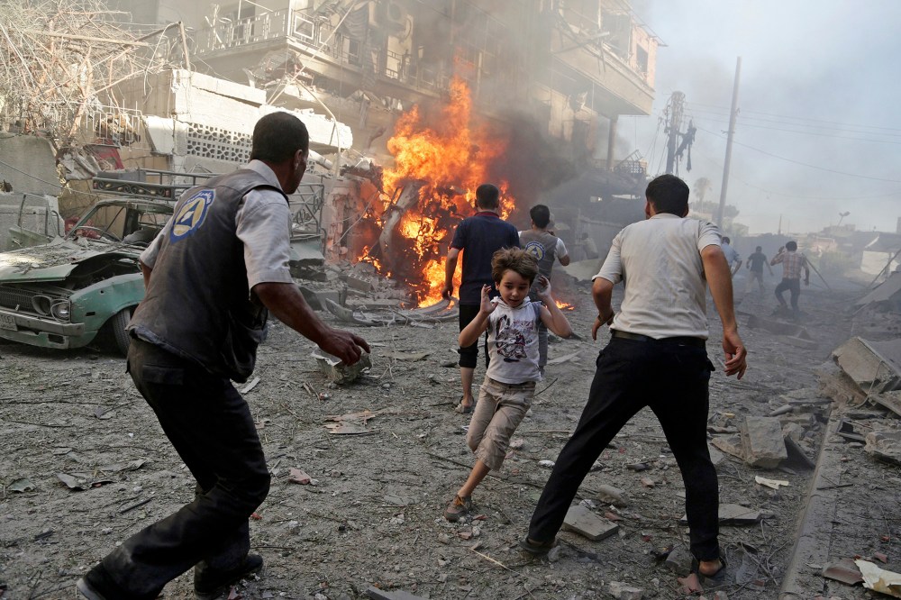 A boy runs as he rushes away from a site hit by what activists said were airstrikes by forces loyal to Syria's President Bashar al-Assad in the Douma neighborhood of Damascus, Syria, Aug. 24, 2015. (Photo by Bassam Khabieh/Reuters)