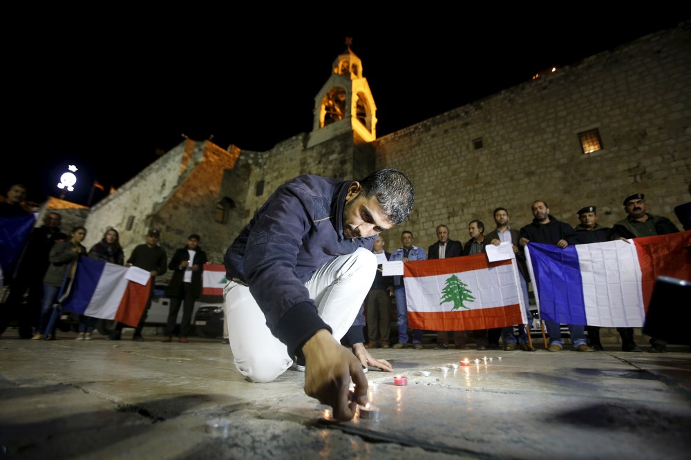 A Palestinian lights a candle during a rally in solidarity with victims of Paris attacks and recent Lebanon bombing, in front of the Nativity church in the West Bank city of Bethlehem, Nov. 14, 2015. (Photo by Mussa Qawasma/Reuters)