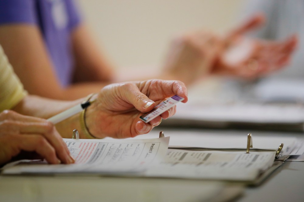 An election worker checks a voter's drivers license at a polling place in Charlotte, N.C. March 15, 2016. (Photo by Chris Keane/Reuters)