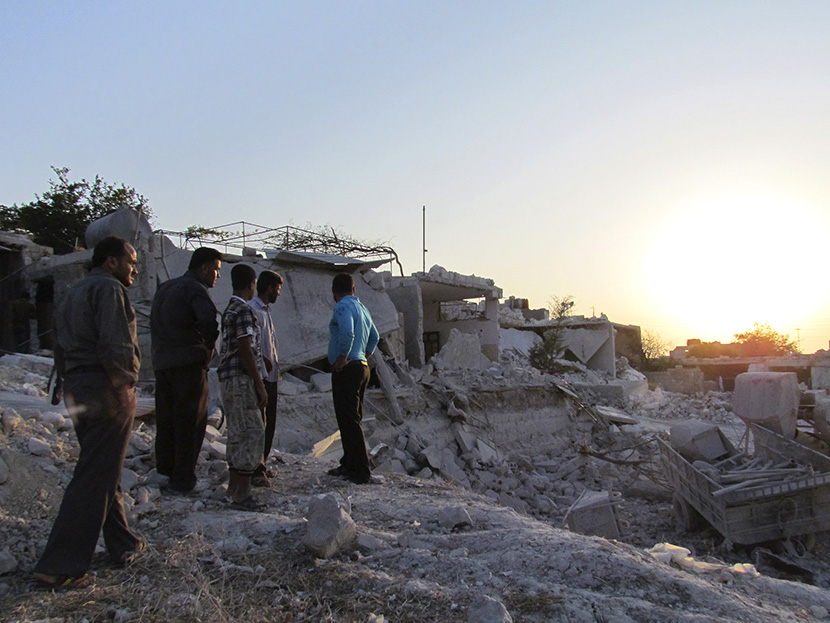 Residents inspect buildings damaged by what activists said were warplanes belonging to forces loyal to Syria's president Al-Assad in Iskat