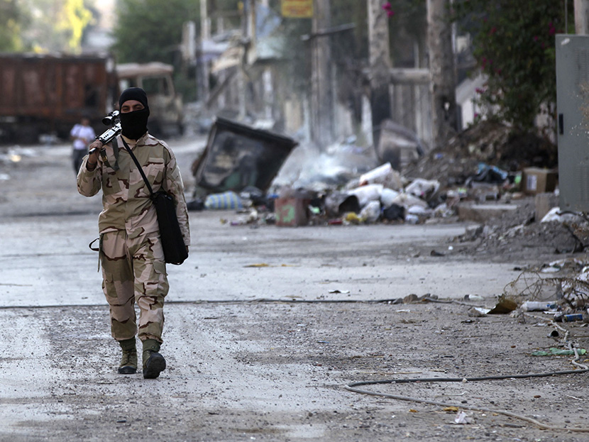 A Free Syrian Army fighter walks with his weapon on a street in Deir al-Zor