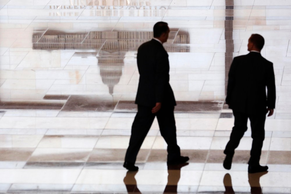 Men walk past a reflected image of the Capitol inside the U.S. Capitol Visitors Center in Washington  October 16, 2013.