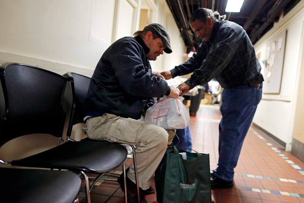 Food pantry handler Kenneth Willis (R) hands out bags of food to Frank Doyle at the Emergency Assistance Program at the Chicago Catholic Charities in Chicago on Nov. 1, 2013