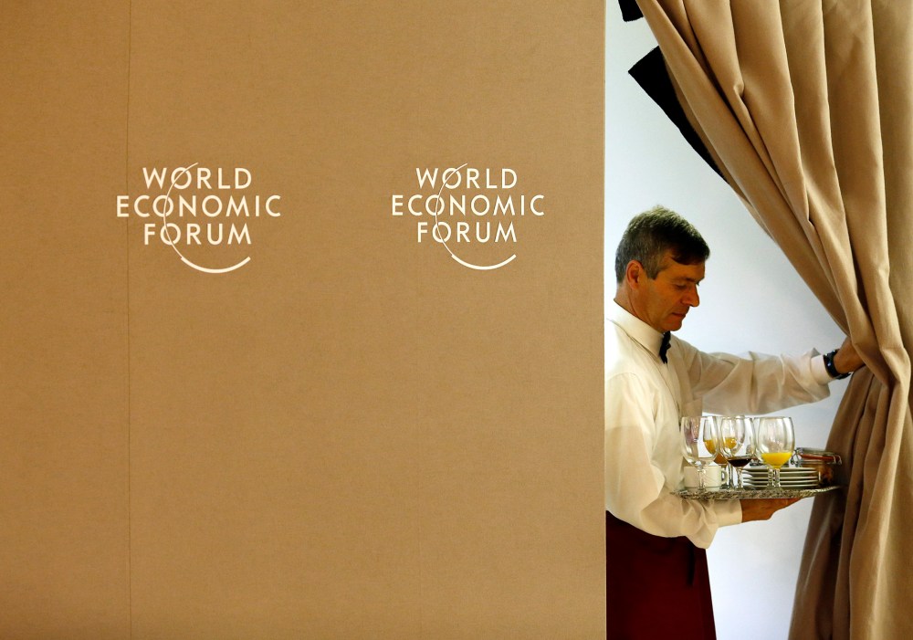 A waiter pulls back a curtain during World Economic Forum in Davos