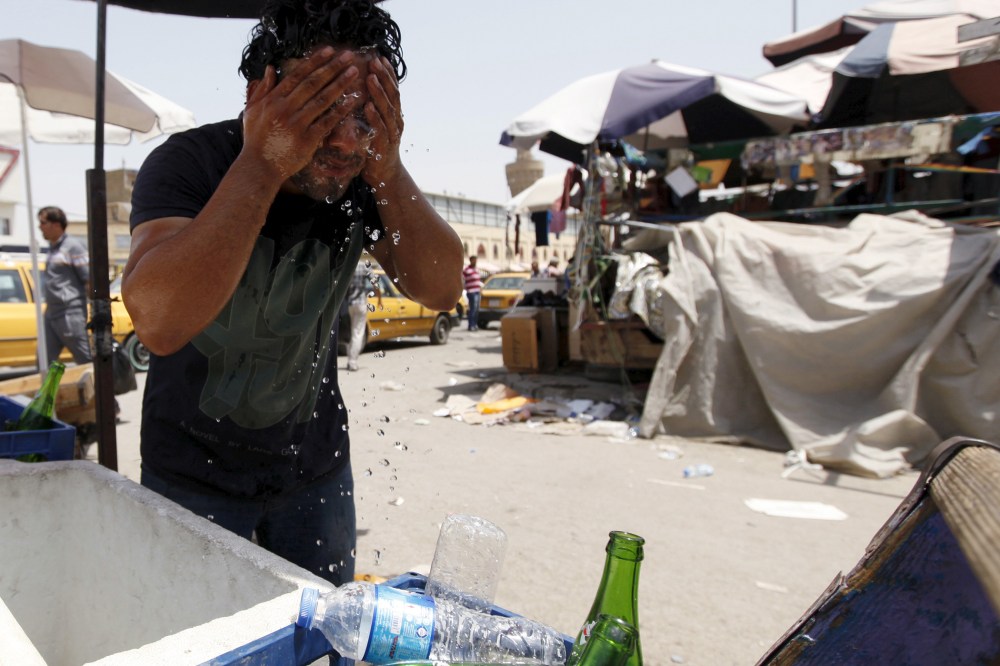 A man washes his face to cool off during a warm summer day in Baghdad (Photo by Ahmed Saad/Reuters).