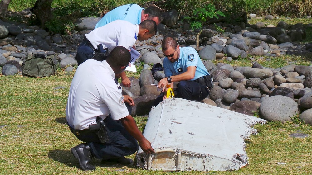 French gendarmes and police inspect a large piece of plane debris which was found on the beach in Saint-Andre, on the French Indian Ocean island of La Reunion, July 29, 2015. (Photo by Prisca Bigot/Zinfos974/Reuters)